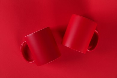 Photo of Two blank mugs on red background, top view. Mockup for design