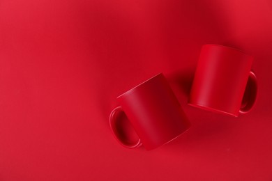 Photo of Two blank mugs on red background, top view. Mockup for design