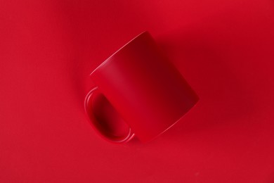 Photo of One blank mug on red background, top view. Mockup for design