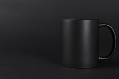 Photo of One blank mug on black background. Mockup for design