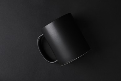 Photo of One blank mug on black background, top view. Mockup for design