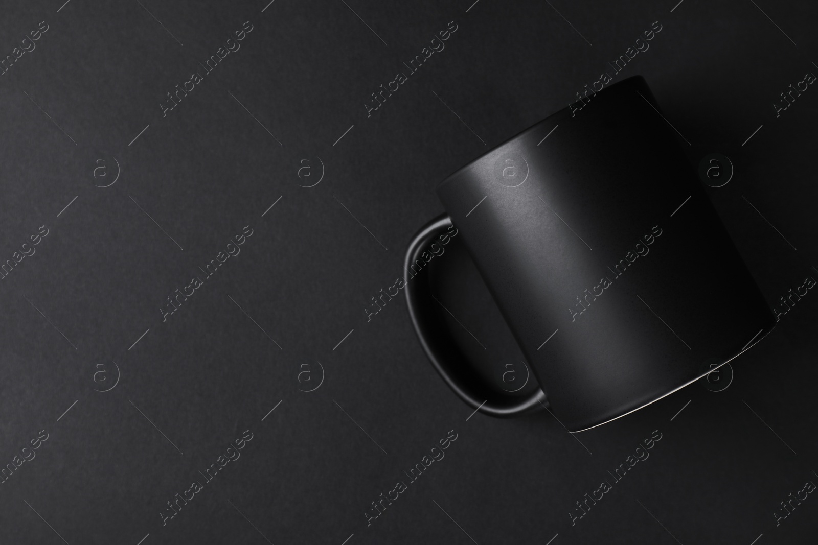 Photo of One blank mug on black background, top view. Mockup for design