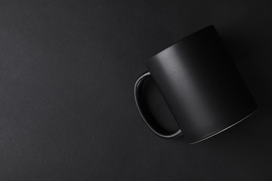 Photo of One blank mug on black background, top view. Mockup for design