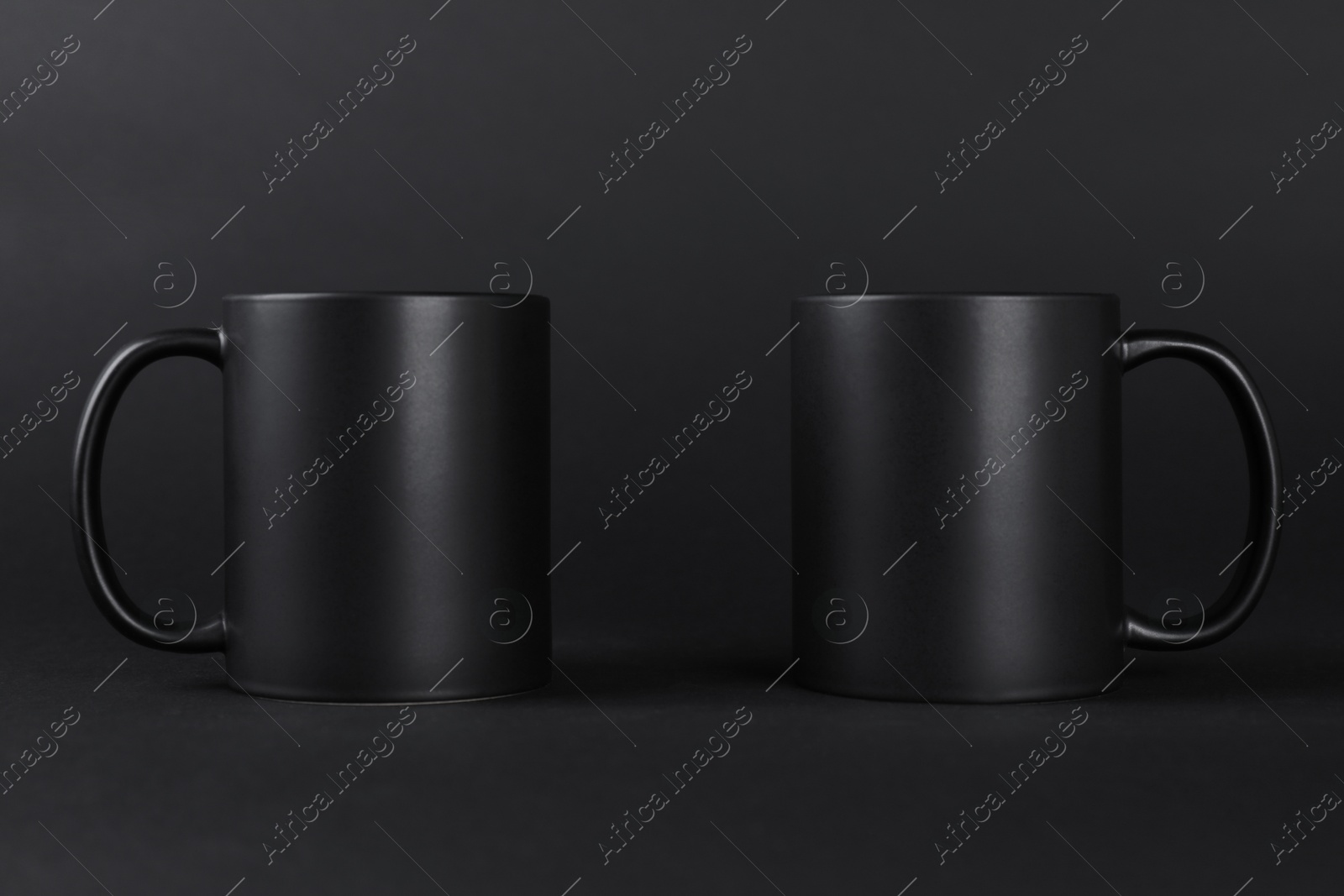 Photo of Two blank mugs on black background. Mockup for design