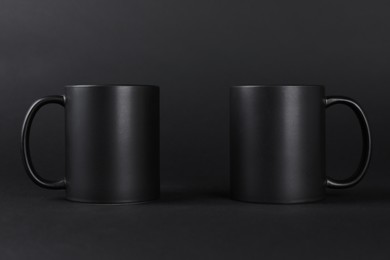 Photo of Two blank mugs on black background. Mockup for design