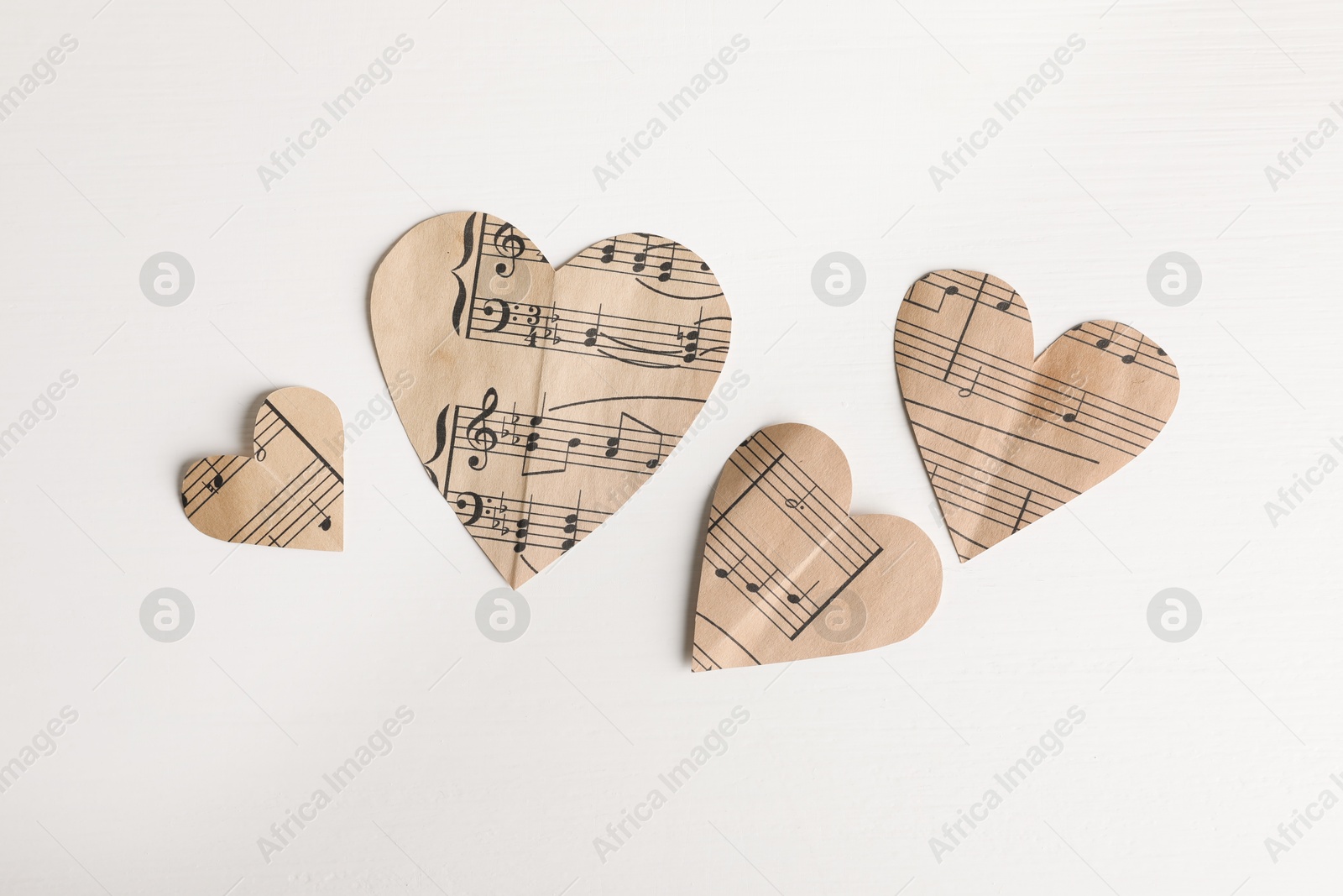 Photo of Paper hearts with notes on white wooden table, flat lay