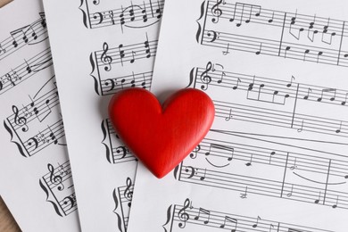 Heart figure and musical note sheets on table, top view