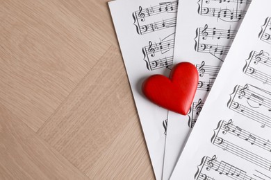 Photo of Heart figure and musical note sheets on wooden table, above view. Space for text