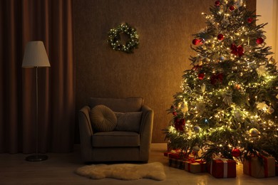 Photo of Cozy room with beautiful Christmas tree, armchair and lamp. Interior design for holiday