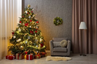 Photo of Cozy room with beautiful Christmas tree, armchair and lamp. Interior design for holiday