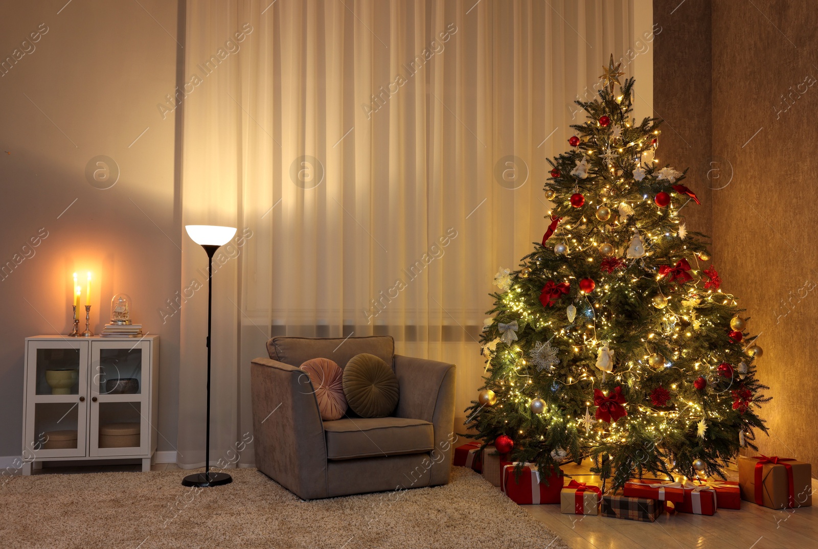 Photo of Cozy room with beautiful Christmas tree, armchair and lamp. Interior design for holiday