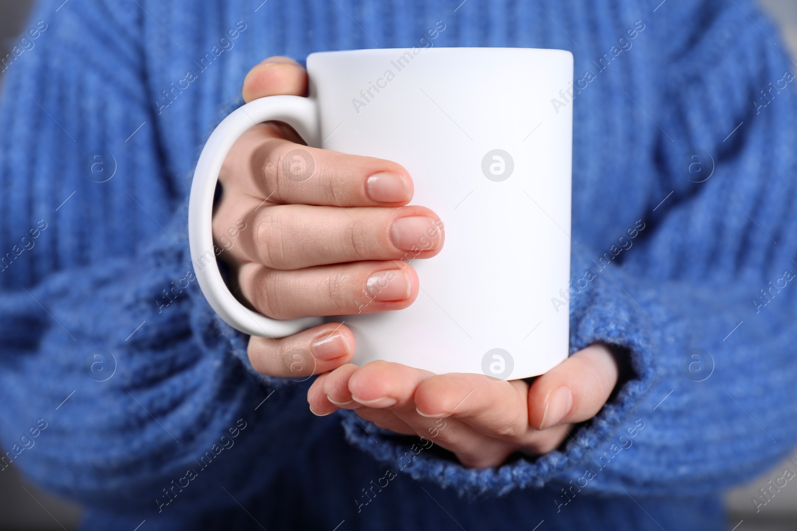 Photo of Woman holding blank white ceramic mug, closeup. Mockup for design