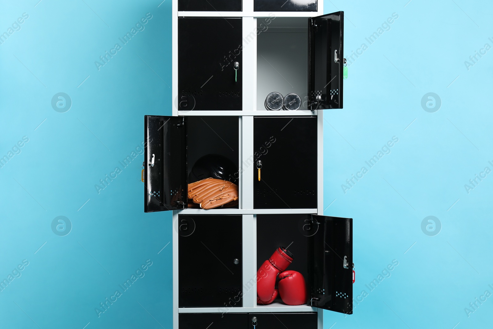 Photo of Open lockers with sport equipment on light blue background