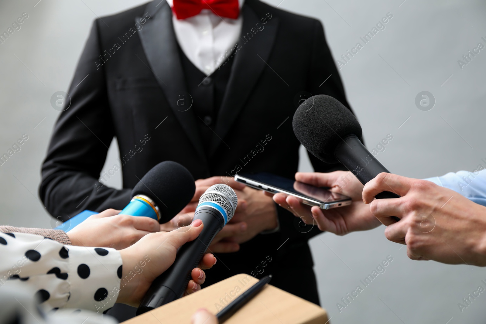 Photo of Group of journalists interviewing businessman on grey background, closeup