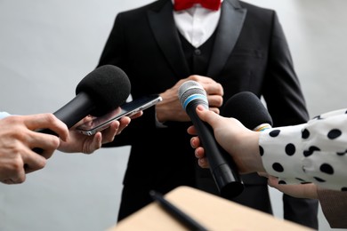 Photo of Group of journalists interviewing businessman on grey background, closeup