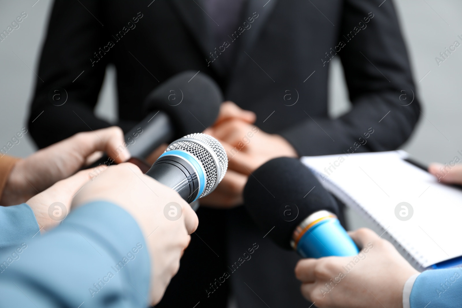 Photo of Group of journalists interviewing businessman on grey background, closeup