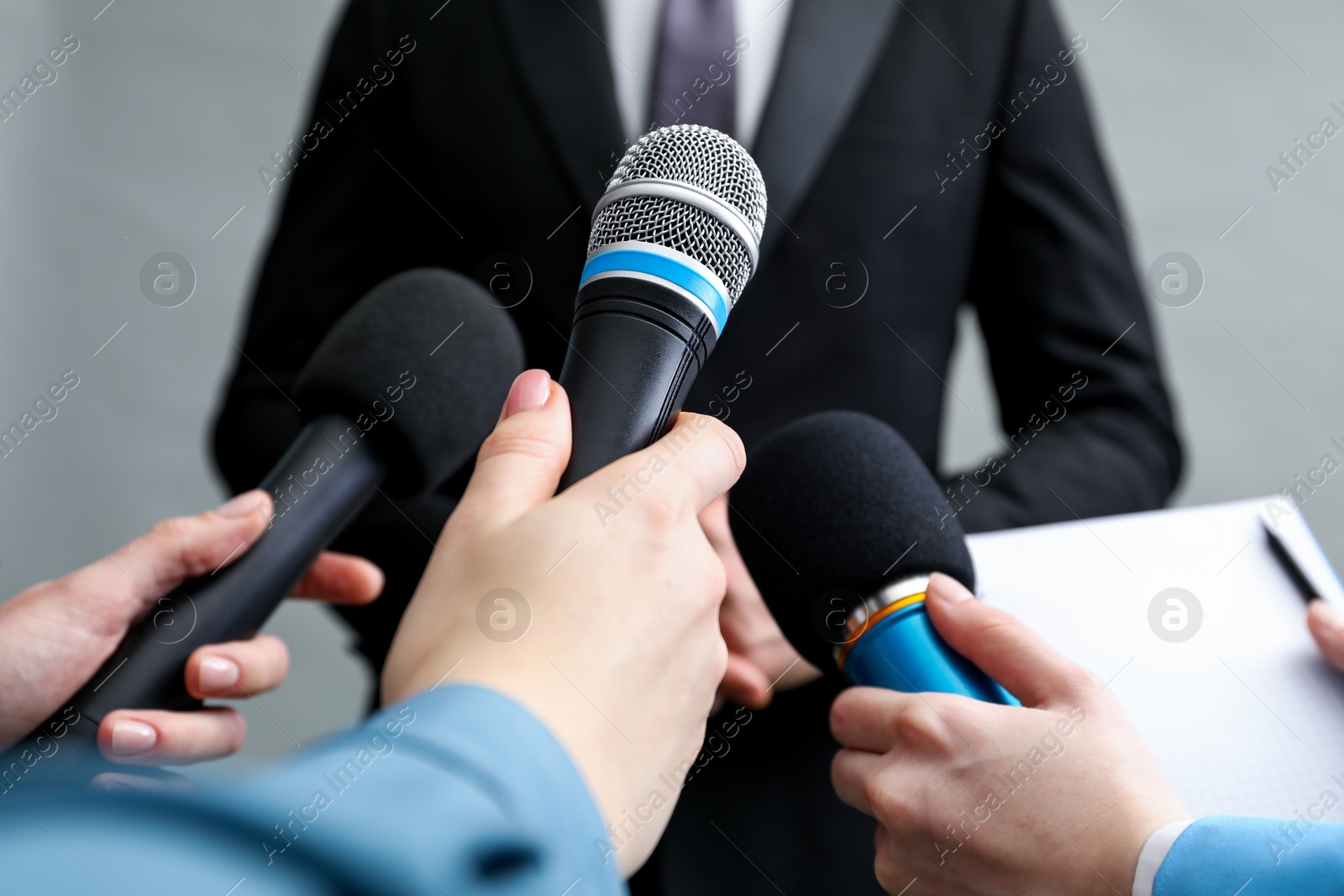 Photo of Group of journalists interviewing businesswoman on grey background, closeup