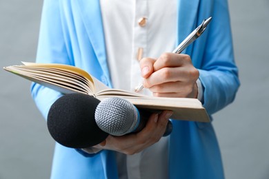 Photo of Journalist with microphones taking notes on grey background, closeup