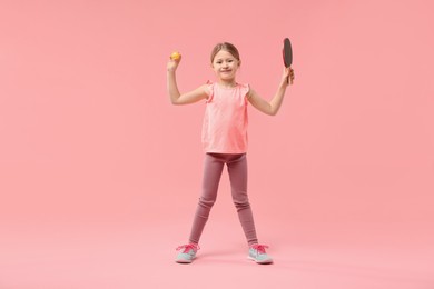 Photo of Cute little girl with ping pong racket and ball on pink background