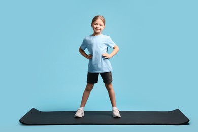 Photo of Cute little girl in sportswear on light blue background