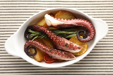 Photo of Fried octopus with vegetables, lemon and rosemary in baking dish on tablecloth, top view