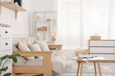 Photo of Beautiful sofa with cushions and coffee table in living room. Interior design