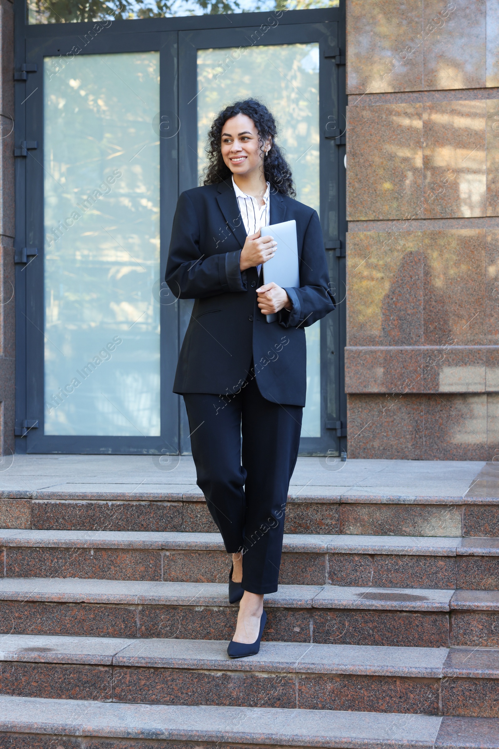 Photo of Portrait of young woman with laptop wearing stylish suit outdoors