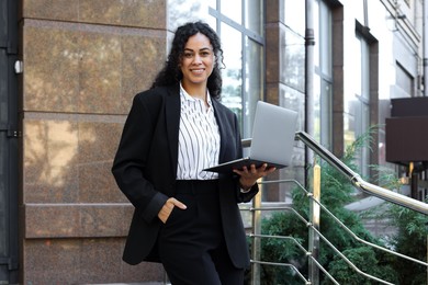 Photo of Portrait of young woman with laptop wearing stylish suit outdoors