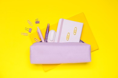 Photo of Pencil case and different stationery on yellow background, flat lay