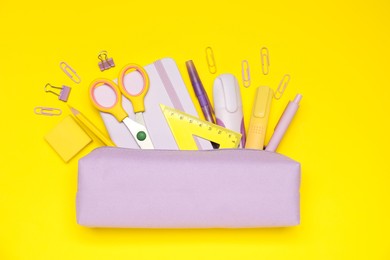 Photo of Pencil case and different stationery on yellow background, flat lay