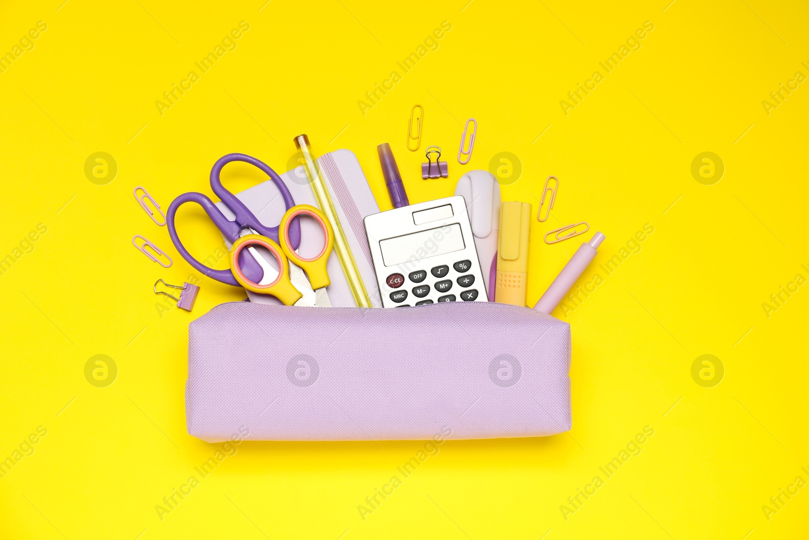 Pencil case and different stationery on yellow background, flat lay Photo of Pencil case and different stationery on yellow background, flat lay