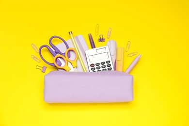 Photo of Pencil case and different stationery on yellow background, flat lay