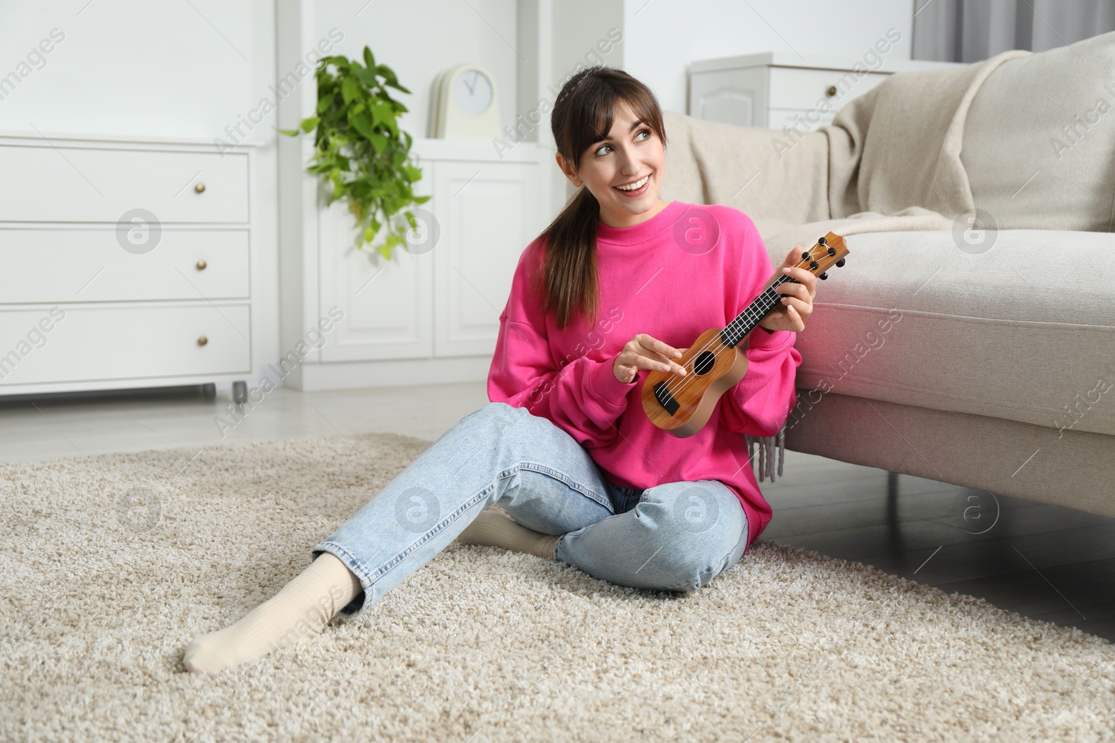 Photo of Happy woman playing ukulele on floor at home