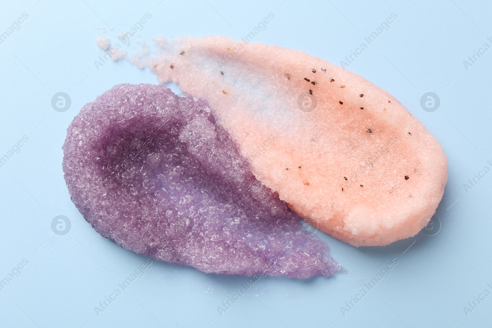 Photo of Samples of body scrubs on light blue background, top view. Skin care