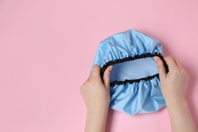 Photo of Woman with shower cap on pink background, top view. Space for text