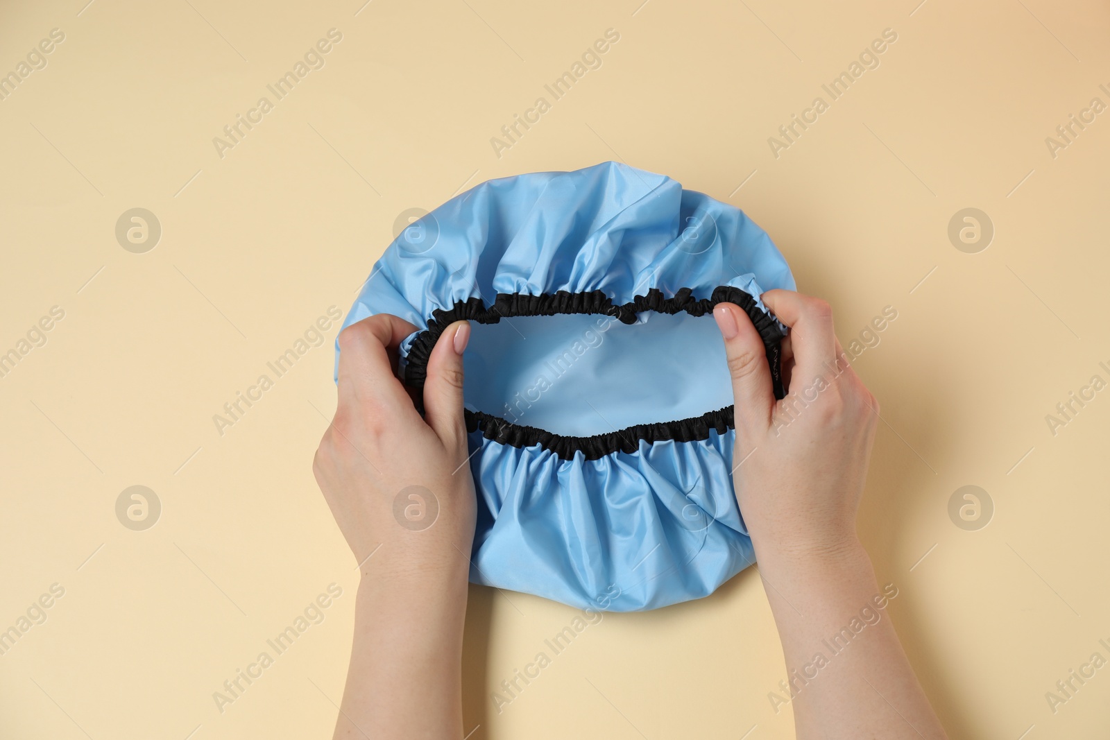 Photo of Woman with shower cap on beige background, top view