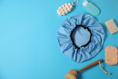 Photo of Shower cap and bath accessories on light blue background, flat lay. Space for text