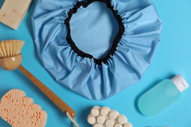 Photo of Shower cap and bath accessories on light blue background, flat lay