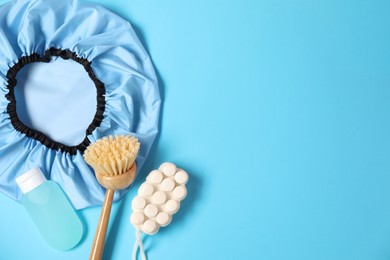 Photo of Shower cap and bath accessories on light blue background, flat lay. Space for text