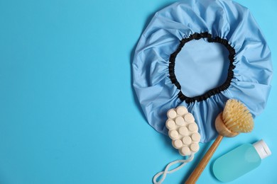 Photo of Shower cap and bath accessories on light blue background, flat lay. Space for text