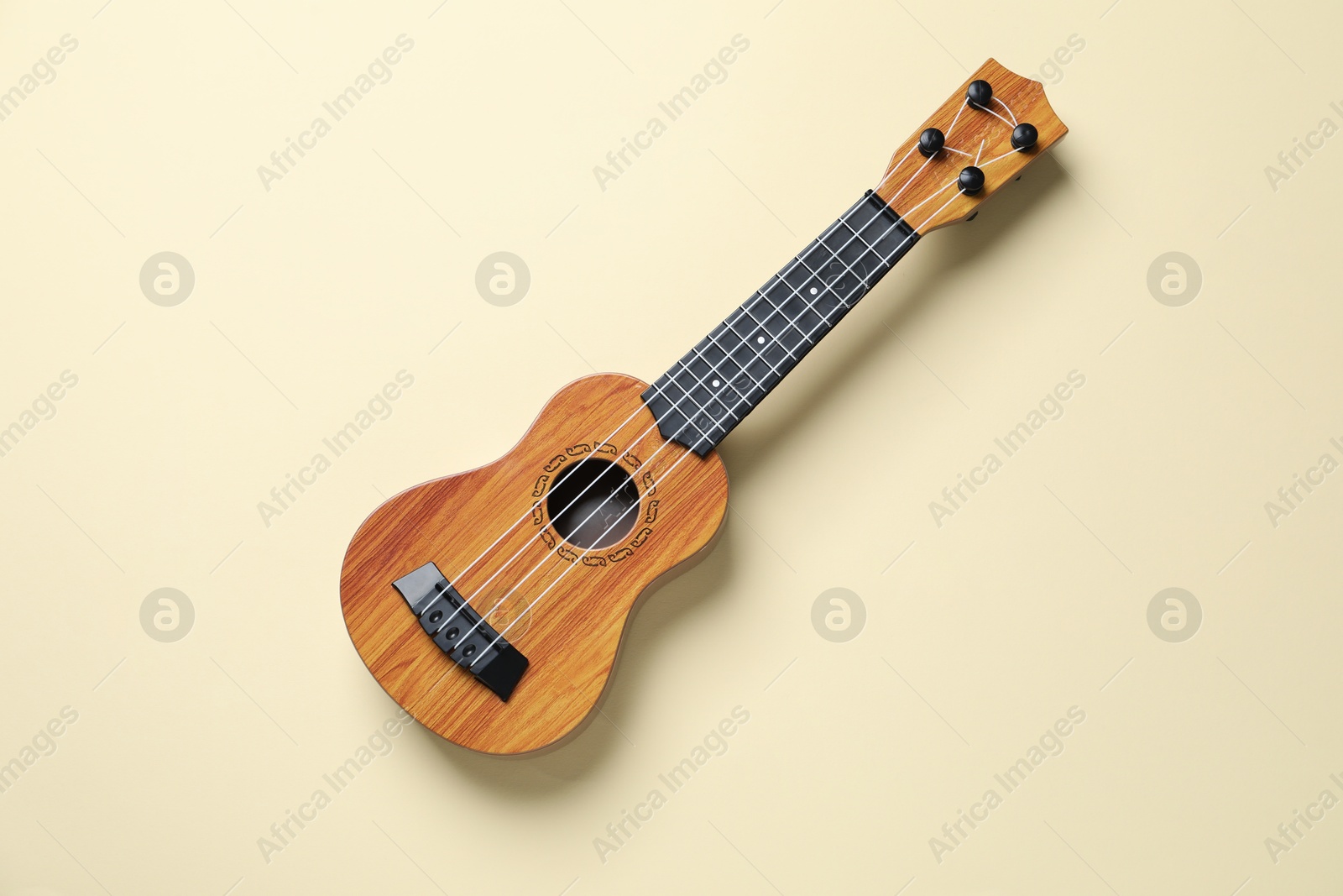 Photo of One ukulele on beige background, top view