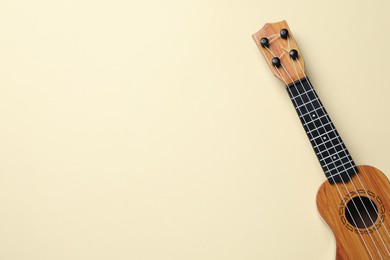 Photo of One ukulele on beige background, top view. Space for text