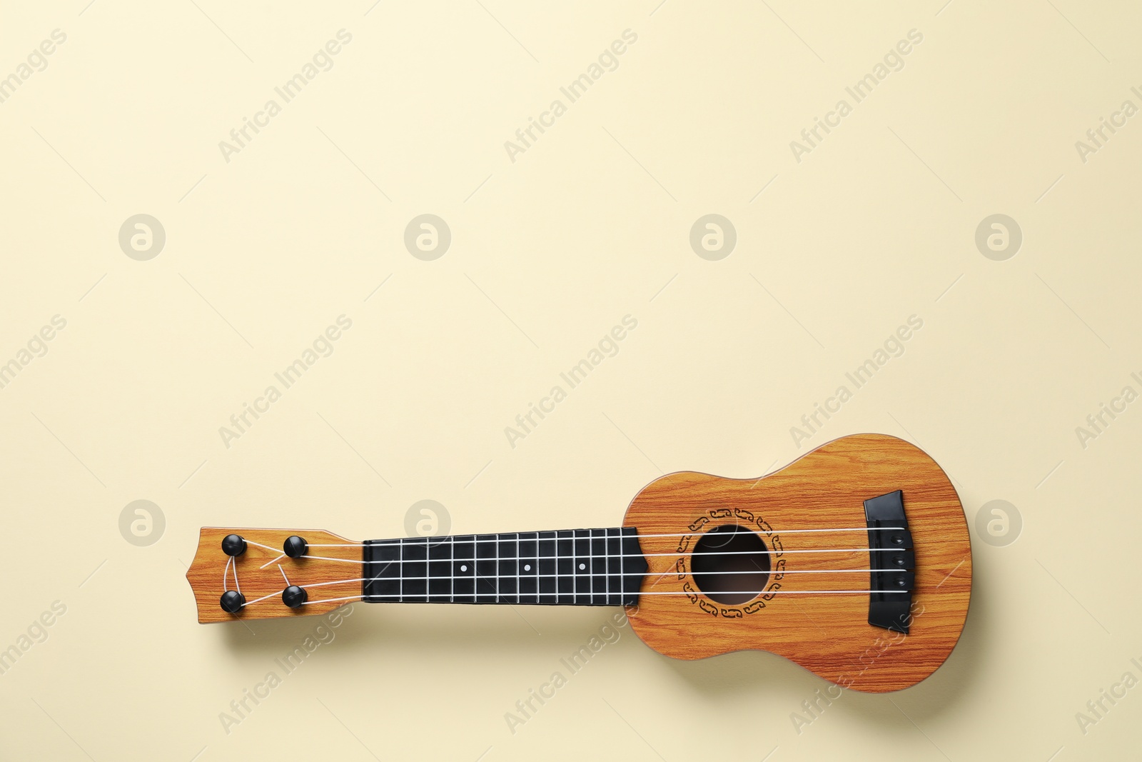 Photo of One ukulele on beige background, top view. Space for text