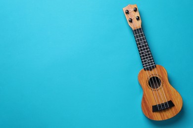 Photo of One ukulele on light blue background, top view. Space for text