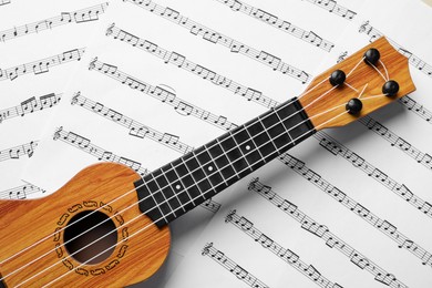 Photo of One ukulele on music sheets, top view