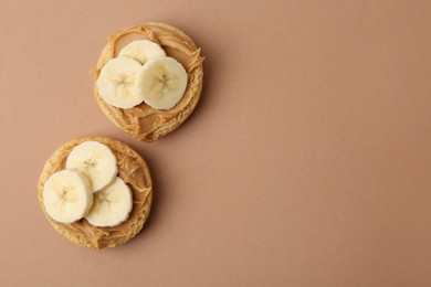 Photo of Tasty sandwiches with peanut butter and banana on brown background, top view. Space for text