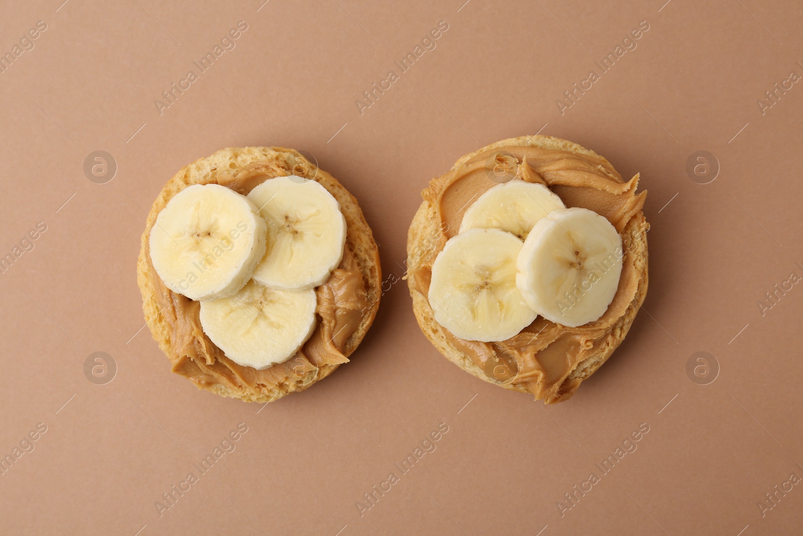 Photo of Tasty sandwiches with peanut butter and banana on brown background, top view