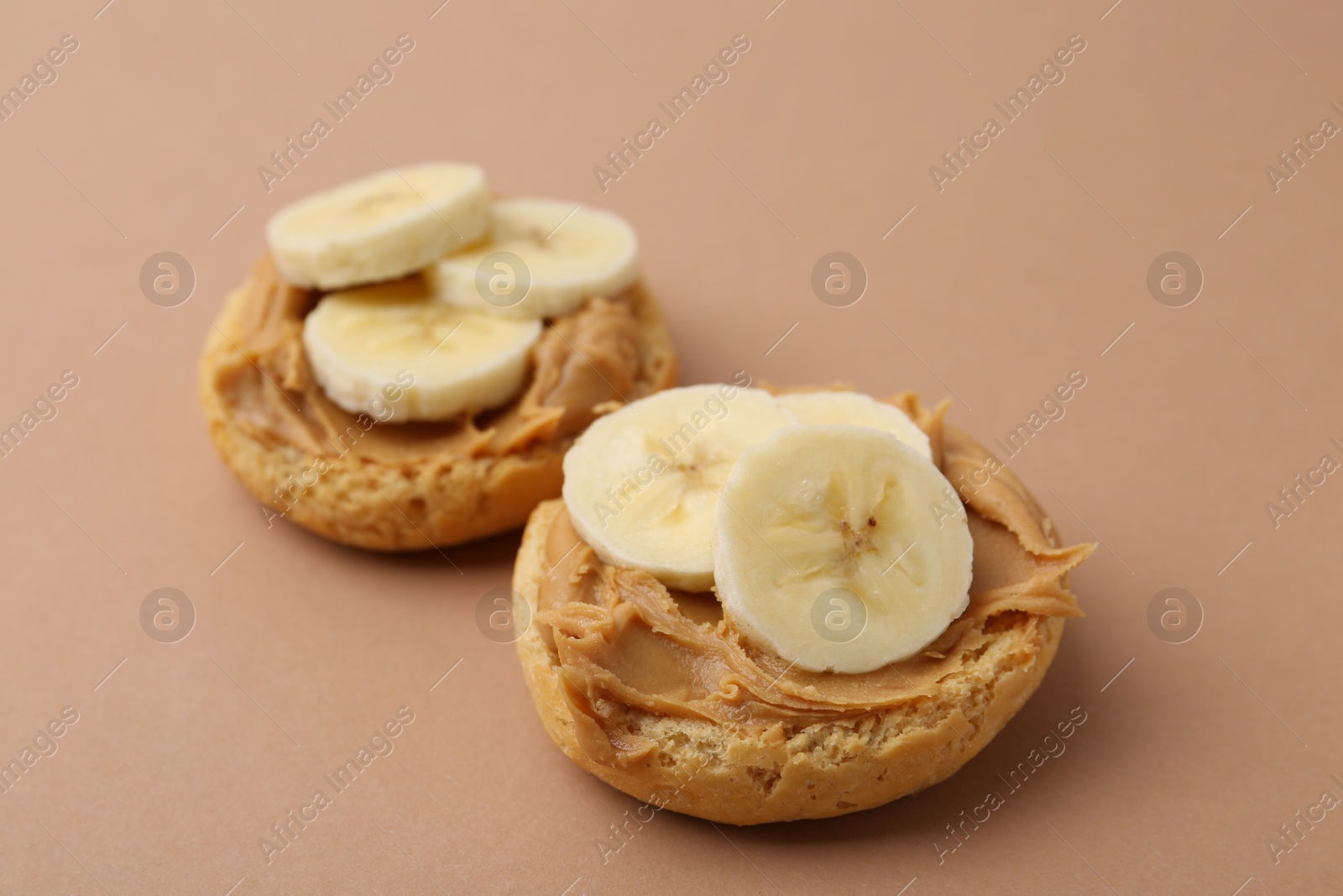 Photo of Tasty sandwiches with peanut butter and banana on brown background, closeup