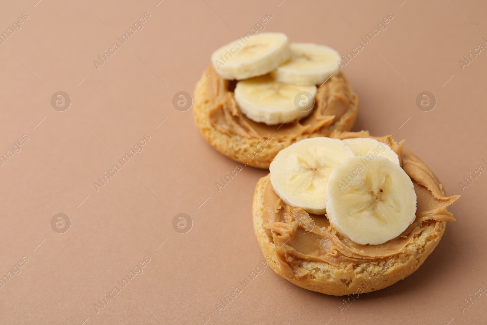 Photo of Tasty sandwiches with peanut butter and banana on brown background, closeup. Space for text