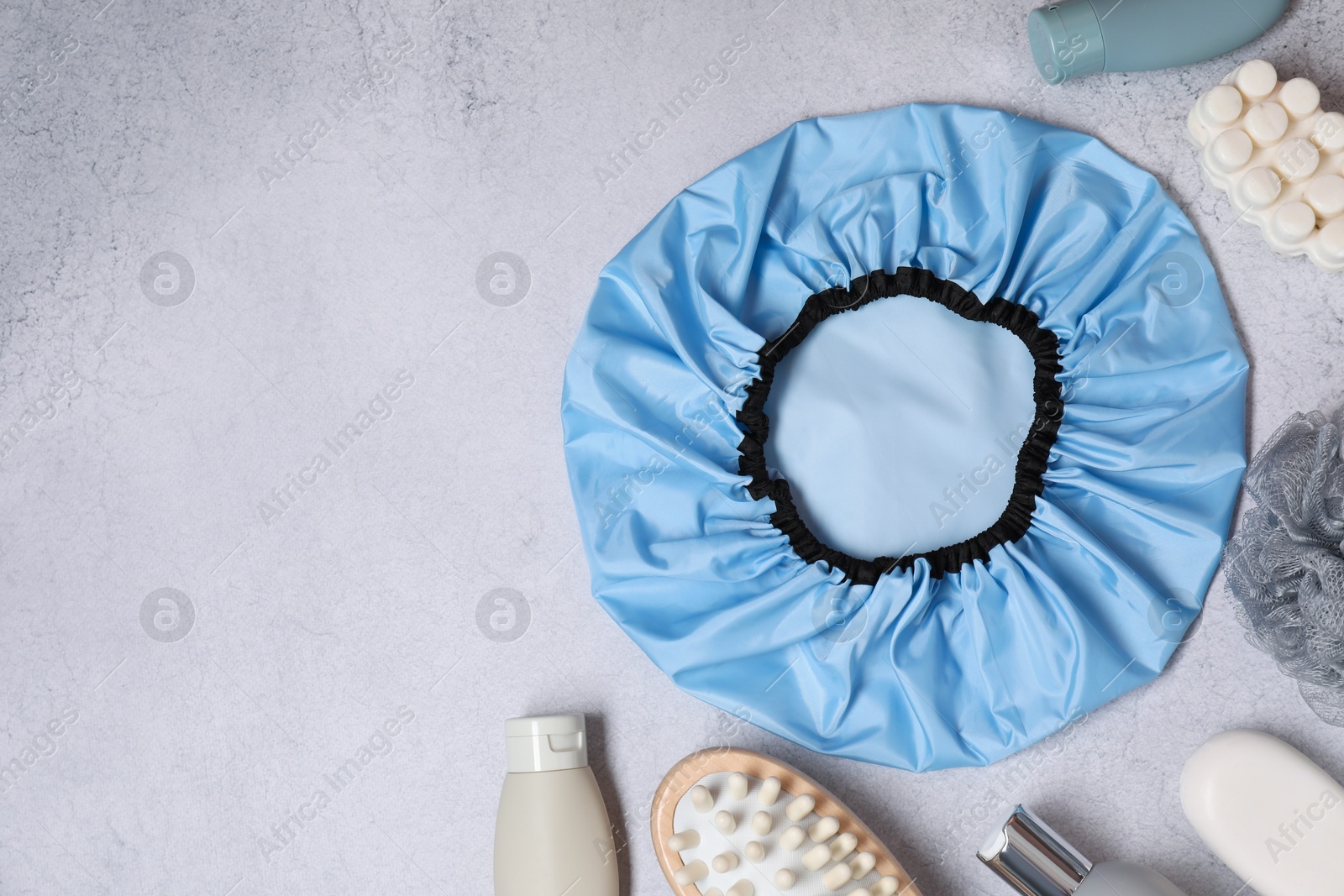 Photo of Shower cap and bath accessories on grey background, flat lay. Space for text